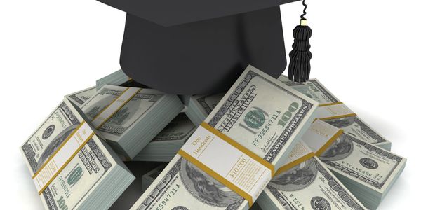 Graduation cap on piles of hundred-dollar bills symbolizing financial success through education.