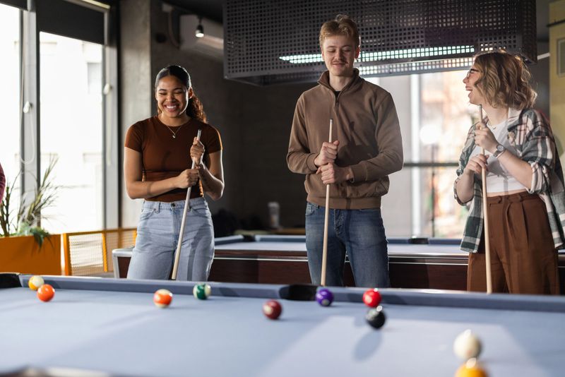 Group of cheerful young multiracial friends playing billiards in a local pool hall