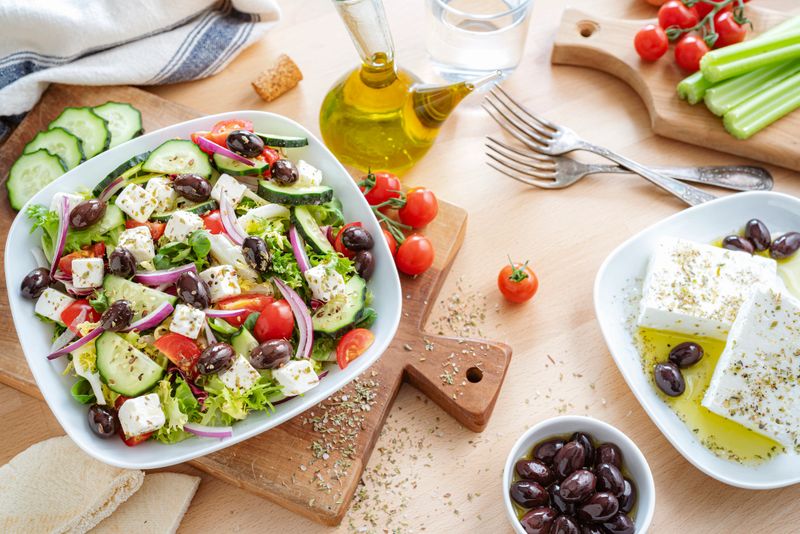 Healthy and fresh Greek salad plate on dining table. Feta cheese, black olives, tomatoes and cucumber