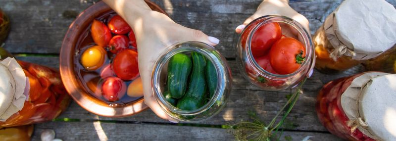 woman canning tomatoes cucumbers vegetables on the background of nature. Selective focus.
