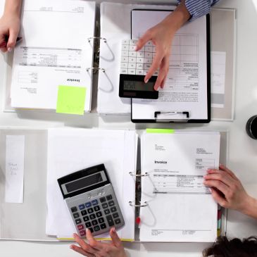People using calculators and reviewing invoices.