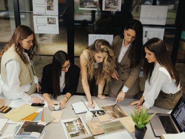 Five women collaborating on interior design plans around a table.