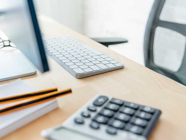 Office desk with keyboard, calculator, pencils, and notepad.