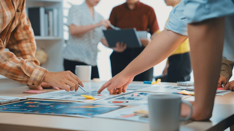 A dynamic scene of teamwork in a modern office, featuring hands engaged in collaborative strategy development and brainstorming, highlighting creativity and effective communication. SACTR