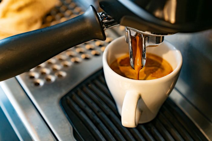 Espresso pouring into two glass cups from a coffee machine.