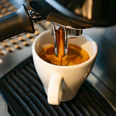 Coffee pouring into a white cup from an espresso machine.