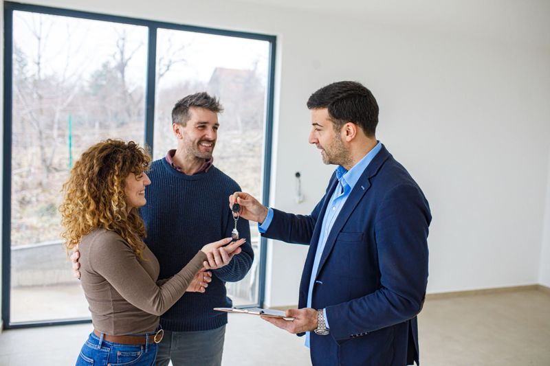 Real estate agent hands over the keys to a new house to a young couple