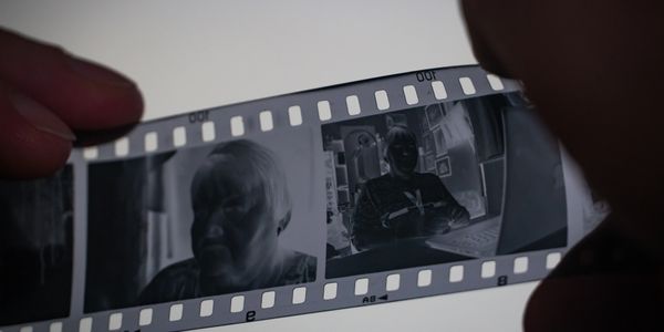 Close-up of a person holding a strip of photographic negatives showing portraits.