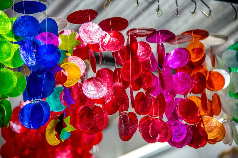 Colorful handcrafted pendants displayed at a vibrant market in Thailand.