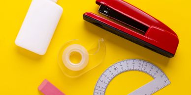 Assorted colorful stationery items on a bright yellow background.