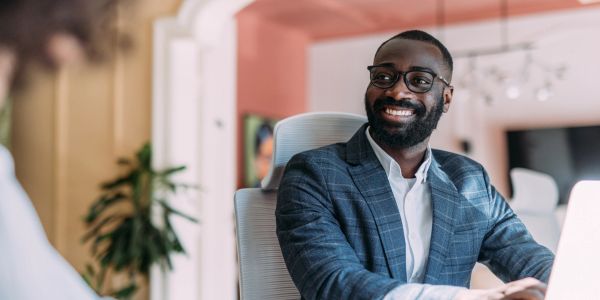 Un homme souriant en costume assis au bureau.