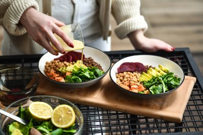Four grilled chicken salads with greens, grapes, walnuts, and dressing containers.