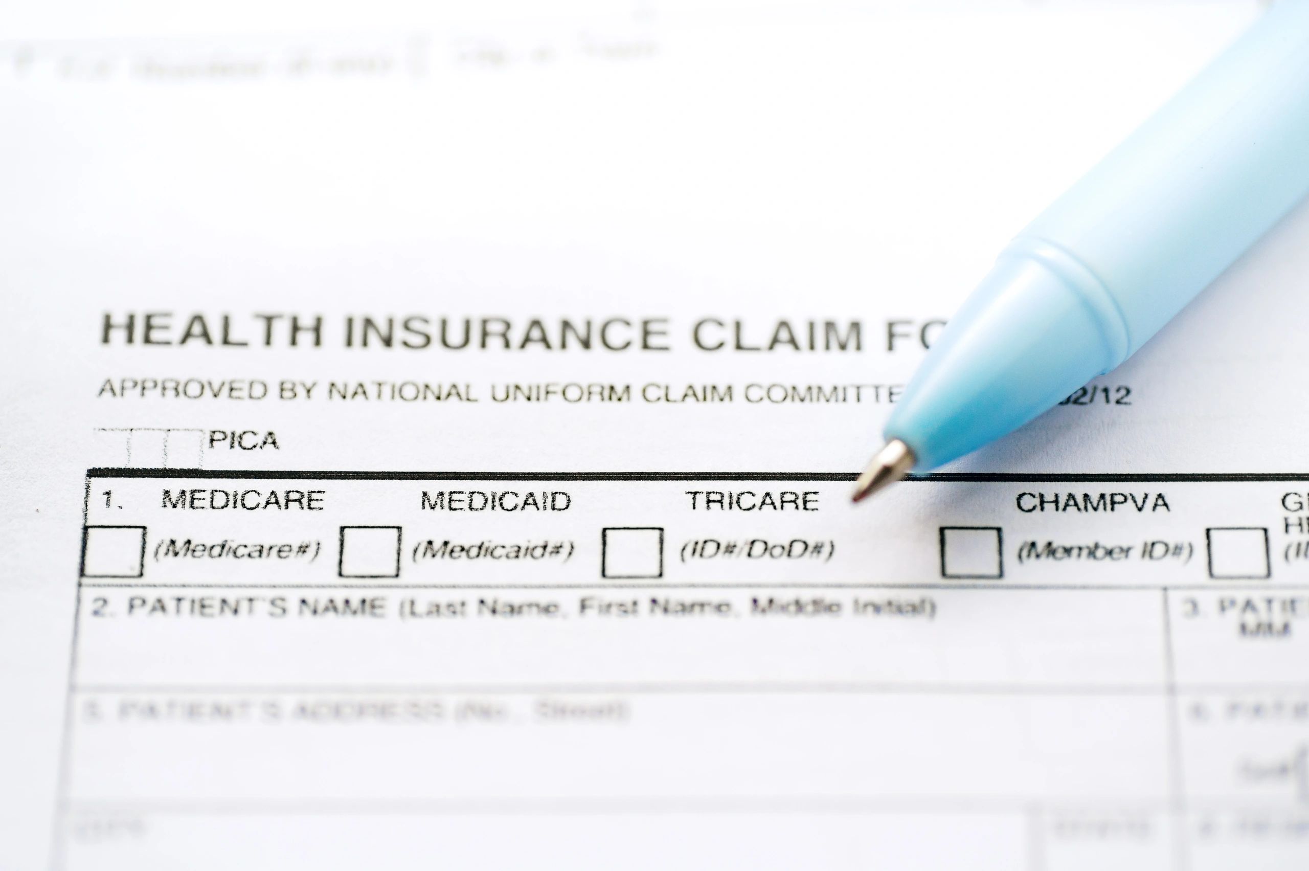 Close-up of a health insurance claim form with a blue pen.