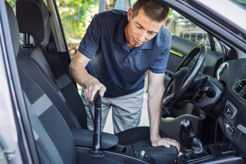 Man is cleaning, wiping and polishing interior of his car.