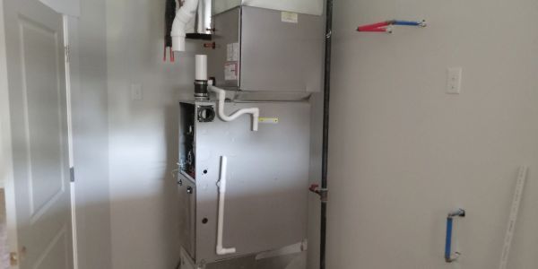 A metal furnace unit installed in a white utility room.