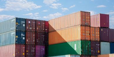 Stacked colorful shipping containers under a sunny sky.