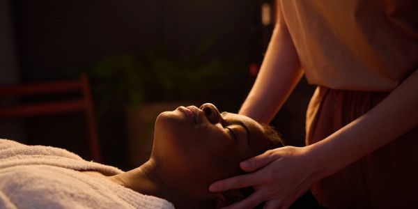 Person receiving a relaxing head massage in dim light.