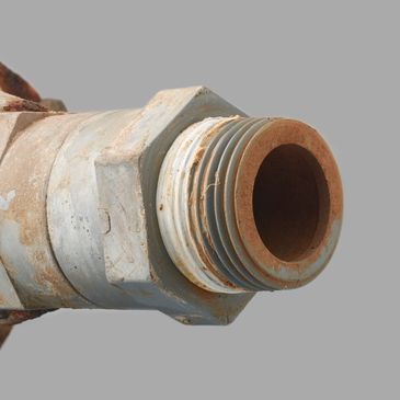 Close-up of a rusty, threaded metal pipe fitting.