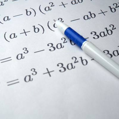 A pen resting on a paper with algebraic expressions and equations.