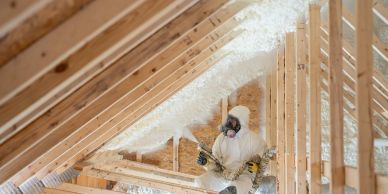 Person spraying insulation foam in attic.