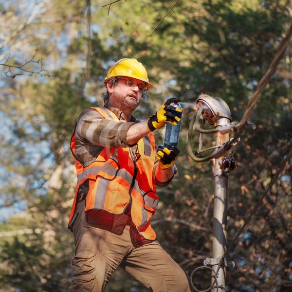 Utility worker spraying spray on electrical equipment outdoors.