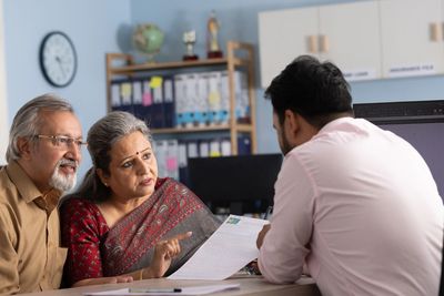 An elderly couple discussing documents with a professional in an office setting.