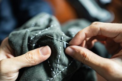 Close-up of hands sewing fabric with needle and thread.