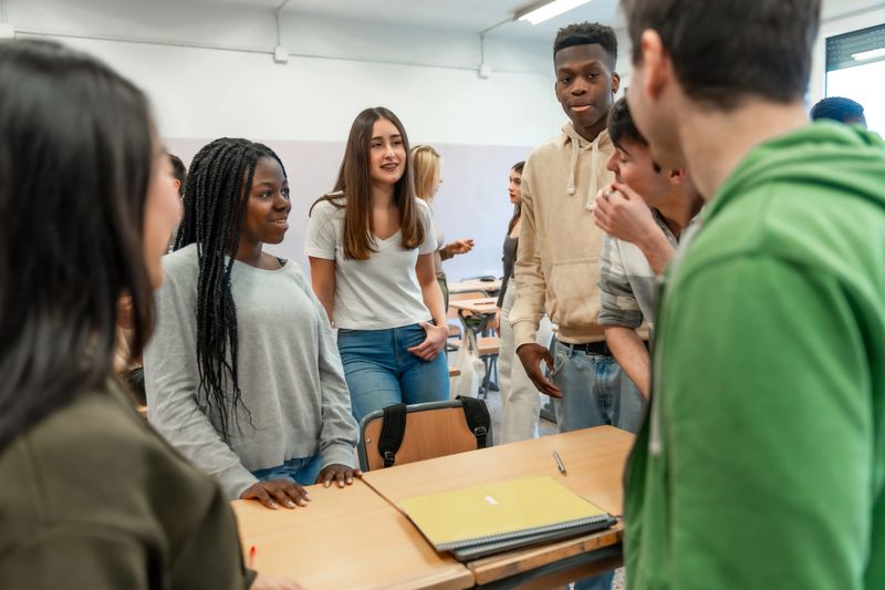Diverse group of high school students collaborating on a project, discussing ideas and working together in a classroom setting