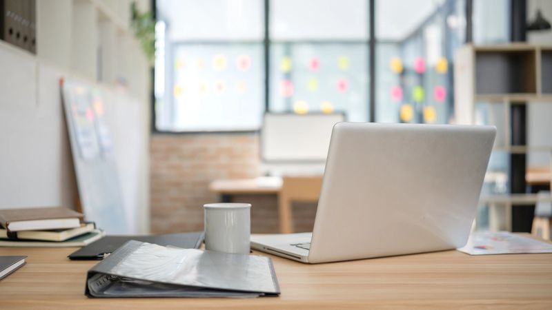Modern office workspace with laptop, coffee, and documents.