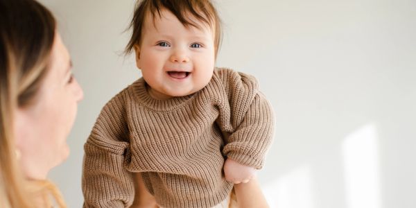 Smiling baby held up by an adult.