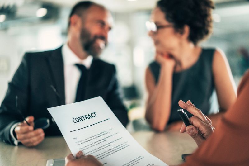 A team of professionals collaborates over a contract during a business meeting. This image emphasizes the importance of negotiation and teamwork in achieving successful outcomes in a corporate environment