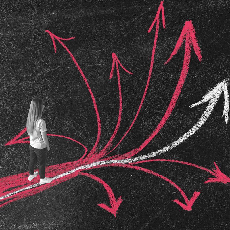 Business, lifestyles concept. Young woman standing on path and looking in bunch of pink chalk arrows with one white arrow. Right choose and make right decisions in life or job concept