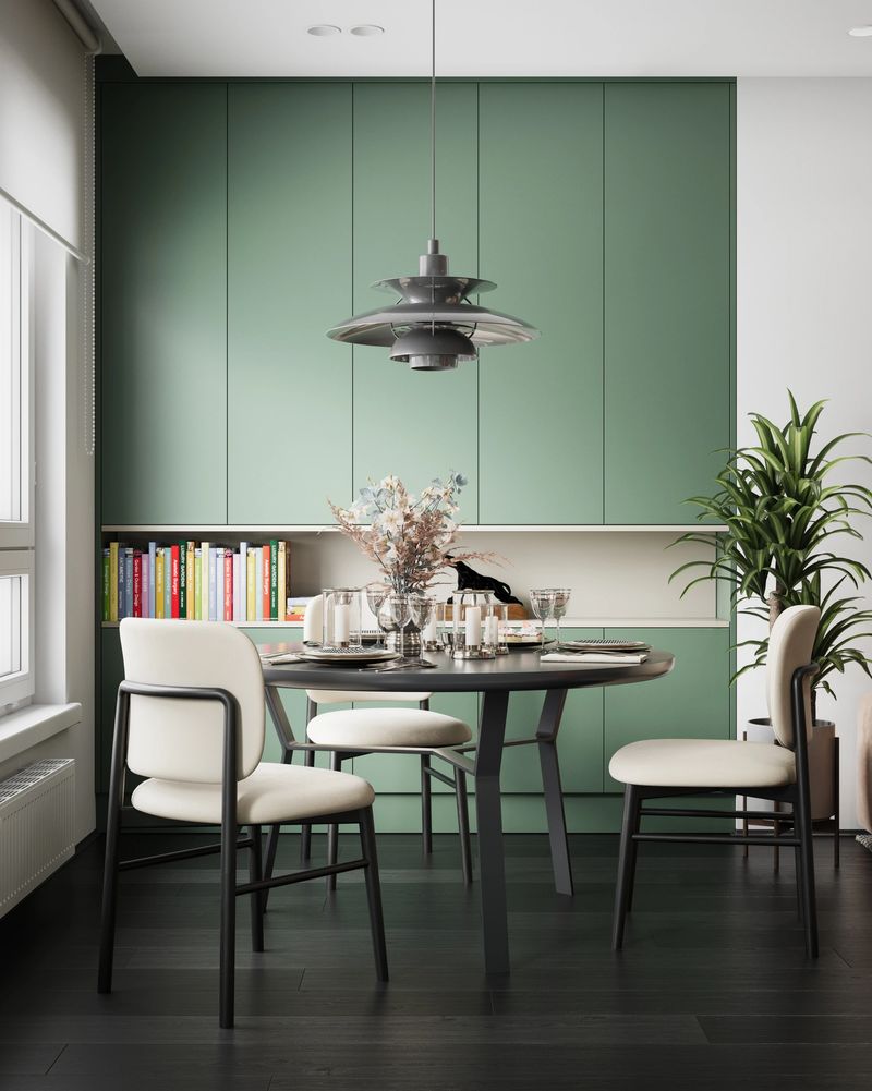 Digitally generated (without the use of any A.I. tools or technologies) stunning dining space that blends mid-century modern influences with contemporary elegance. The soft sage green cabinetry, sleek black dining table, and plush white chairs create a refined yet inviting atmosphere. A statement pendant light adds a touch of retro charm, reminiscent of 1960s Danish modern design. The bookshelf, adorned with colorful reads, along with lush greenery, brings warmth and personality to the space. A perfect balance of sophistication and coziness, this modern home setting is ideal for intimate dining and stylish living.

The scene was created in Autodesk® 3ds Max 2025 with V-Ray 7 and rendered with photorealistic shaders and lighting in Chaos® Vantage with some post-production added.