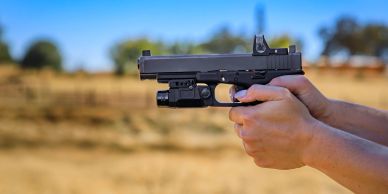 Person holding a handgun outdoors.