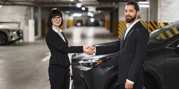 Two professionals shaking hands in a parking garage.