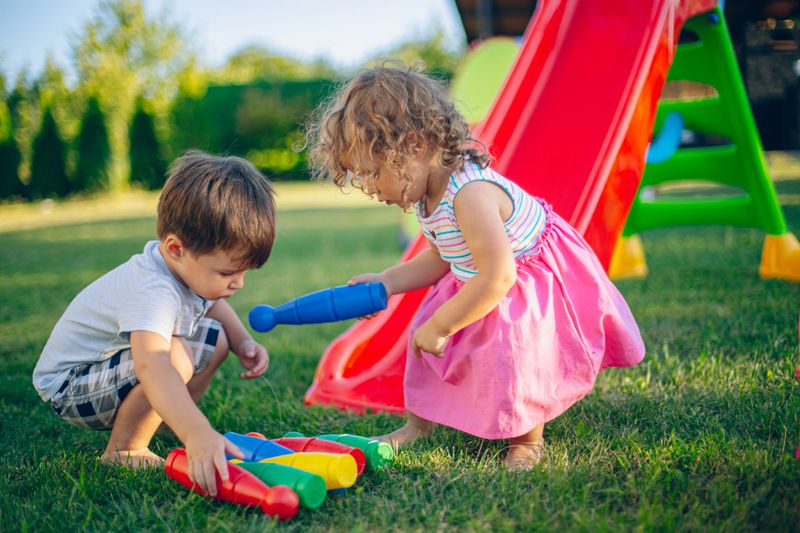 Girl and boy playing in their backyard playground in the summer