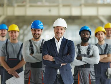Smiling construction team with a manager in a hard hat standing confidently.