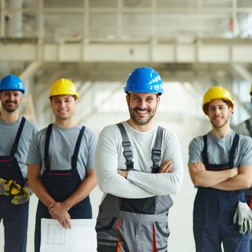 Group of construction workers wearing helmets and smiling.