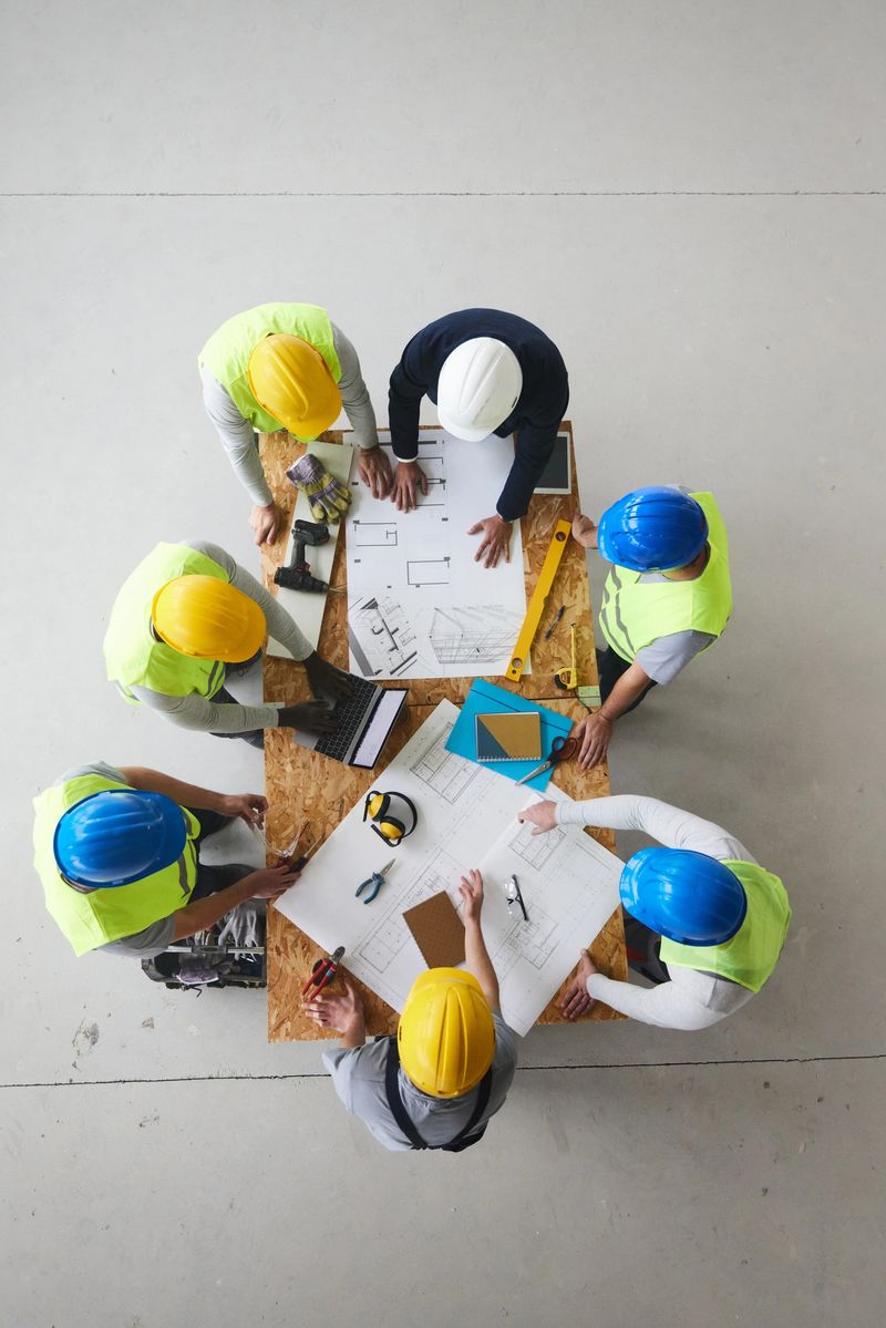 High angle view of a male project manager and team of workers going through rebuilding plans at construction site. Copy space.