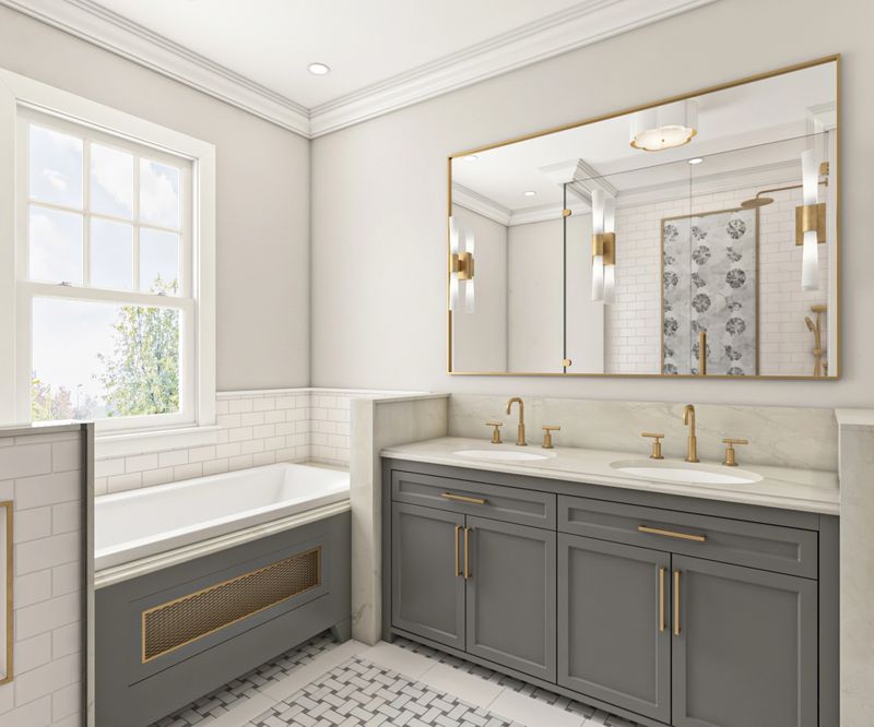 Elegant modern bathroom featuring gray cabinetry, gold fixtures, marble countertops, a spacious bathtub, and a large mirror with beautiful lighting for a bright and luxurious finish.