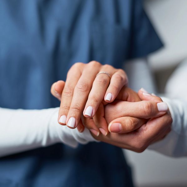 Two people holding hands, showing support and care.