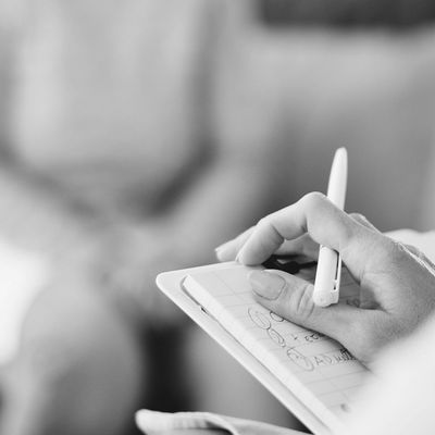 A person holding a pen and clipboard, possibly in a counseling or consultation setting.