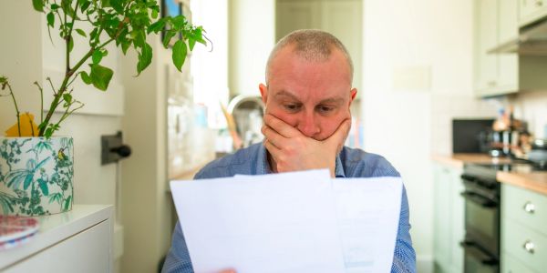 A man looks worried while reading documents at home.