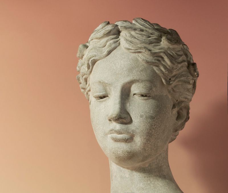 A detailed stone sculpture of a female bust, blending classical art with subtle modern tones. Set against a warm gradient background, evoking a sense of elegance and cultural appreciation.