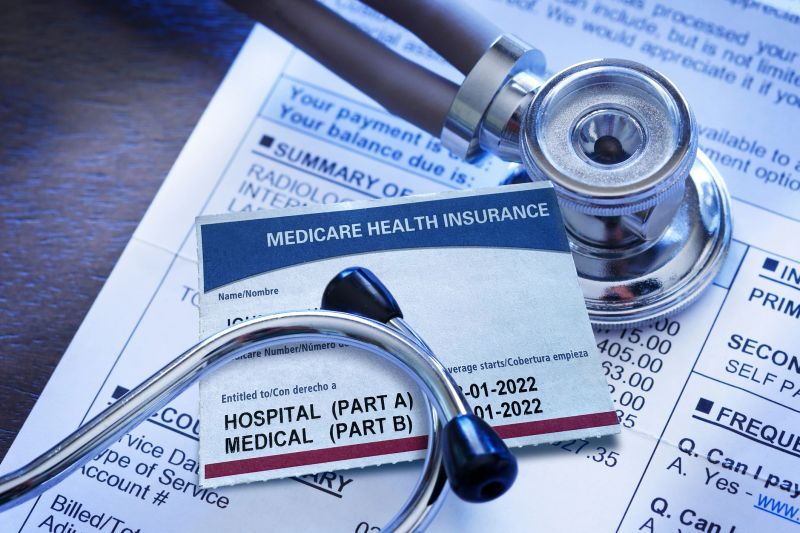 A Medicare insurance card and a stethoscope rest on top of a hospital medical invoice.