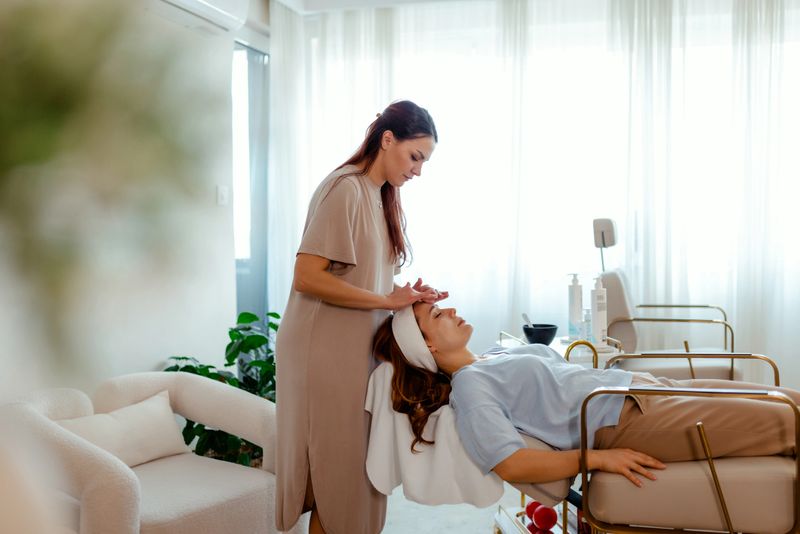 A beauty therapist carefully massages a client's face, promoting skincare and wellness in a serene spa environment. The image captures a moment of peace, relaxation, and self-care.