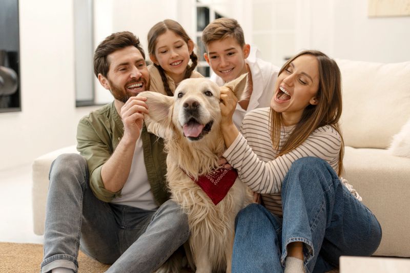 Smiling parents and children enjoying playful moments with their pet dog, a golden retriever wearing a red bandana, while sitting on the living room floor, radiating joy and togetherness