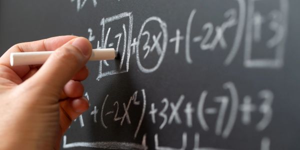 Hand writing complex math equation on chalkboard.