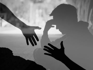 Hand reaching out for another, man stressed in the background