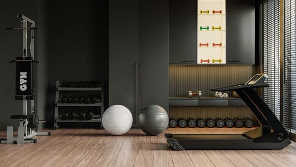 Modern gym room with treadmill, dumbbells, and exercise balls on wood flooring.